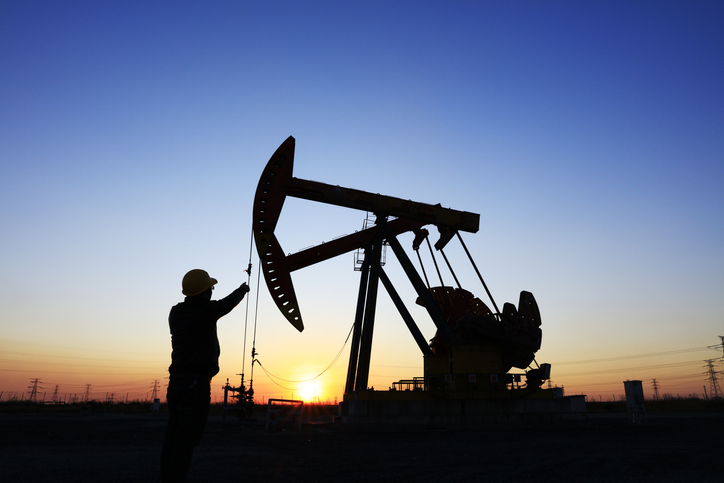 Oil rig drilling at sunset with worker
